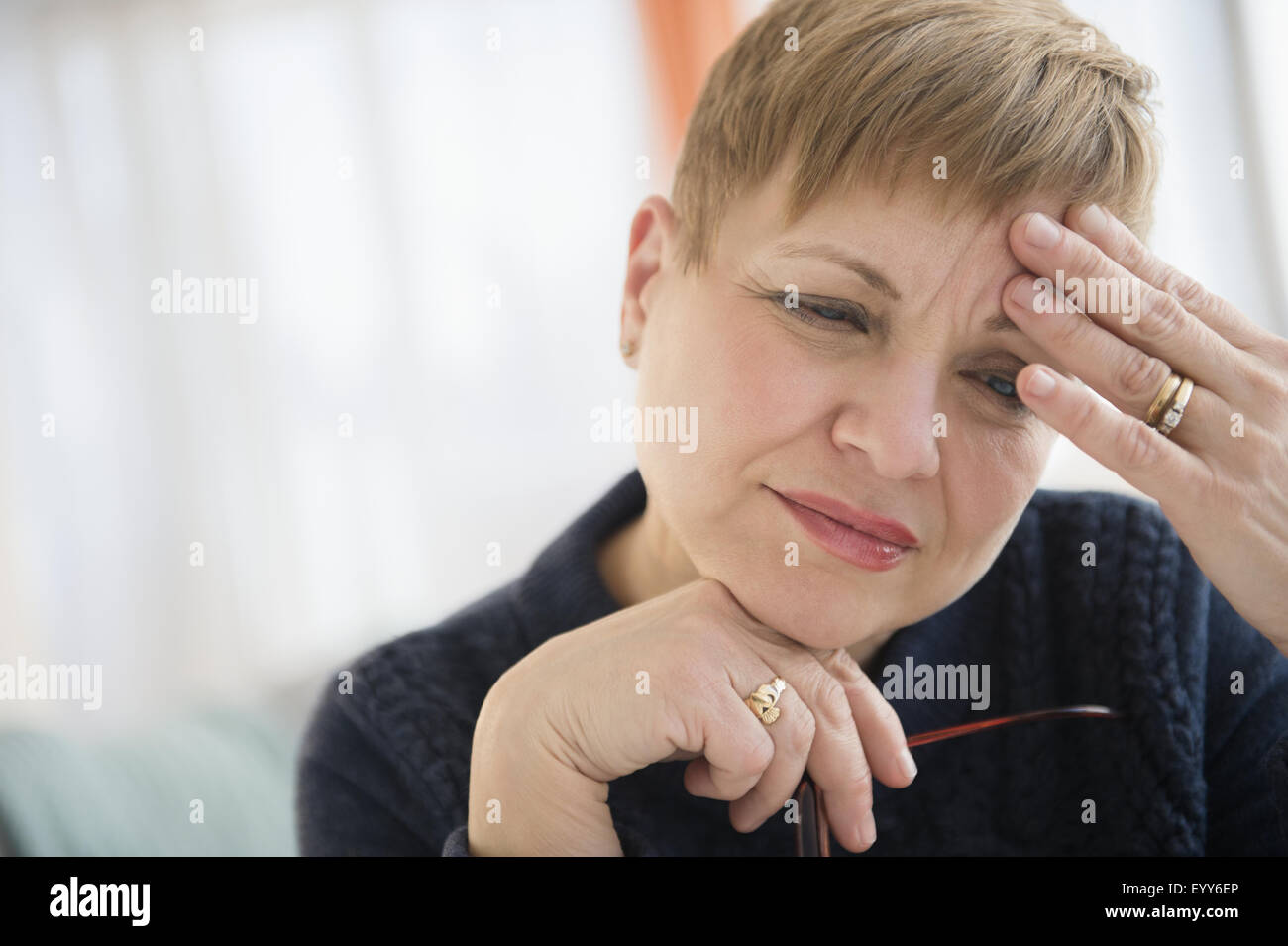 Anxious Caucasian woman rubbing forehead Stock Photo