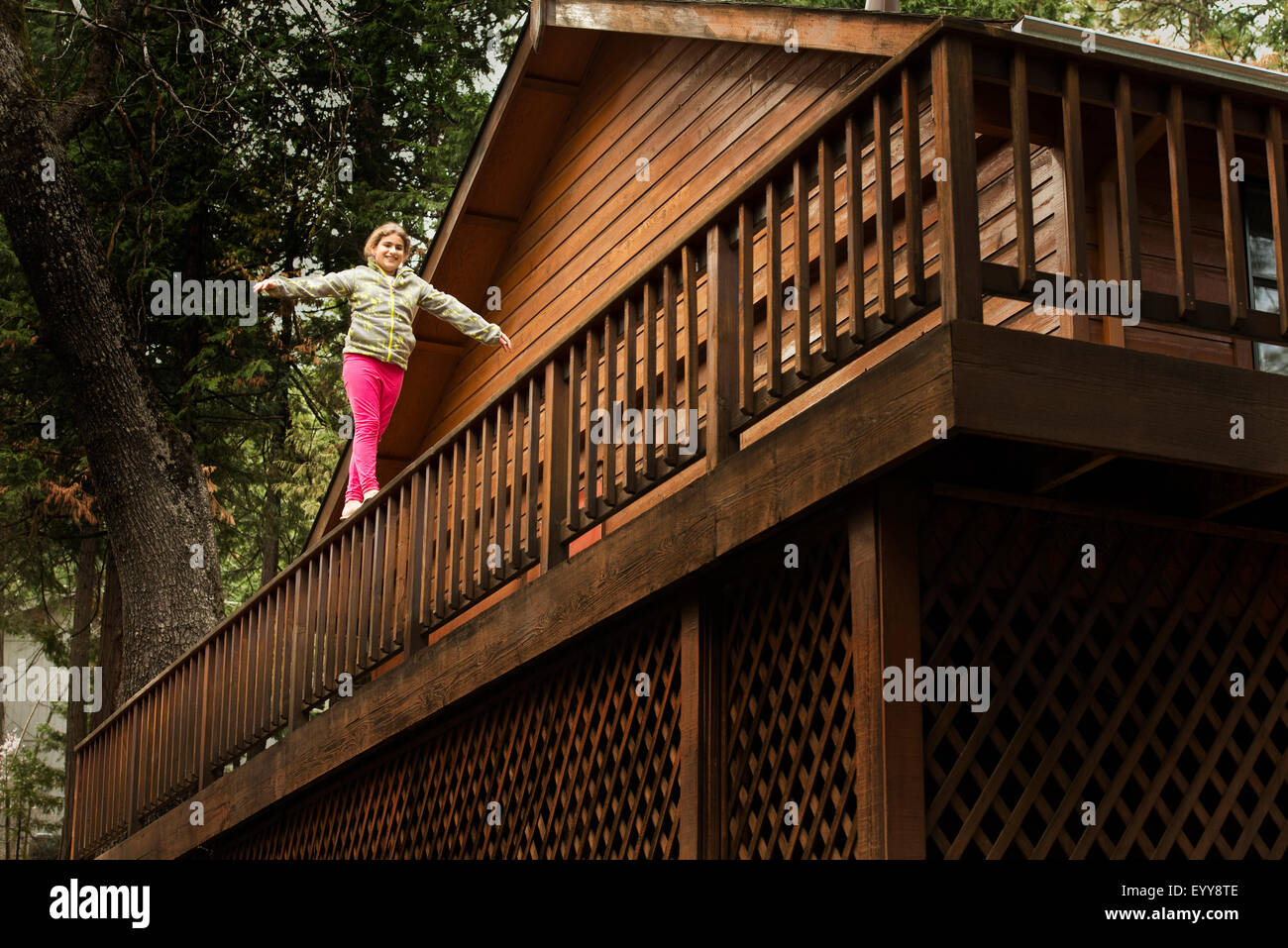 Mixed race girl balancing on balcony banister Stock Photo