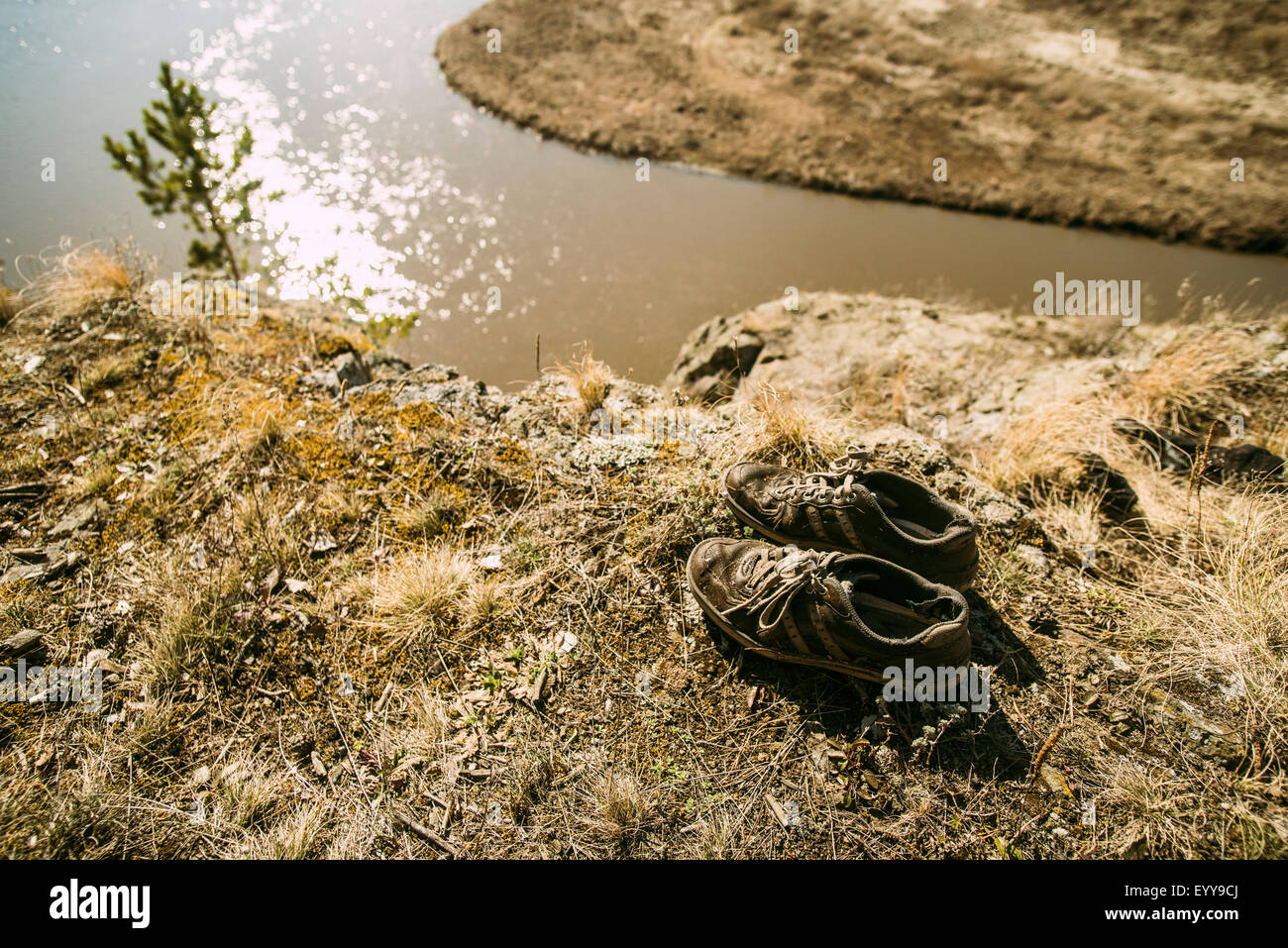 Close up of abandoned shoes over remote river Stock Photo