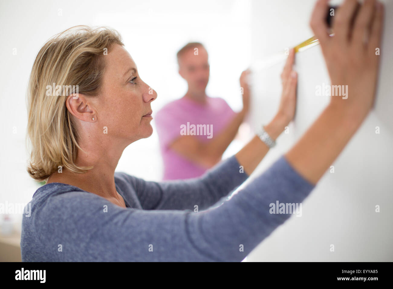 Couple measuring wall in new home Stock Photo
