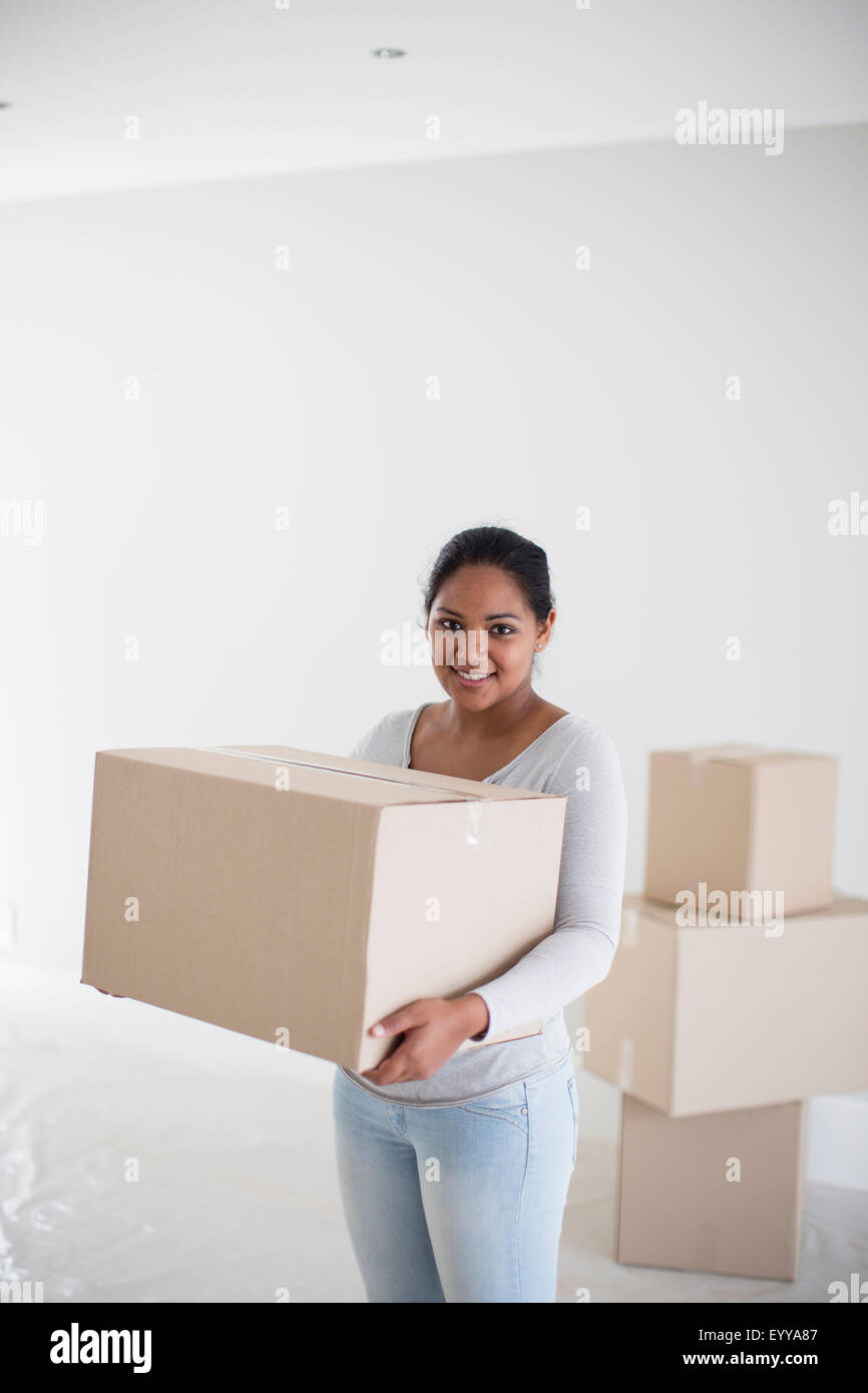 Mixed race woman carrying cardboard box in new home Stock Photo