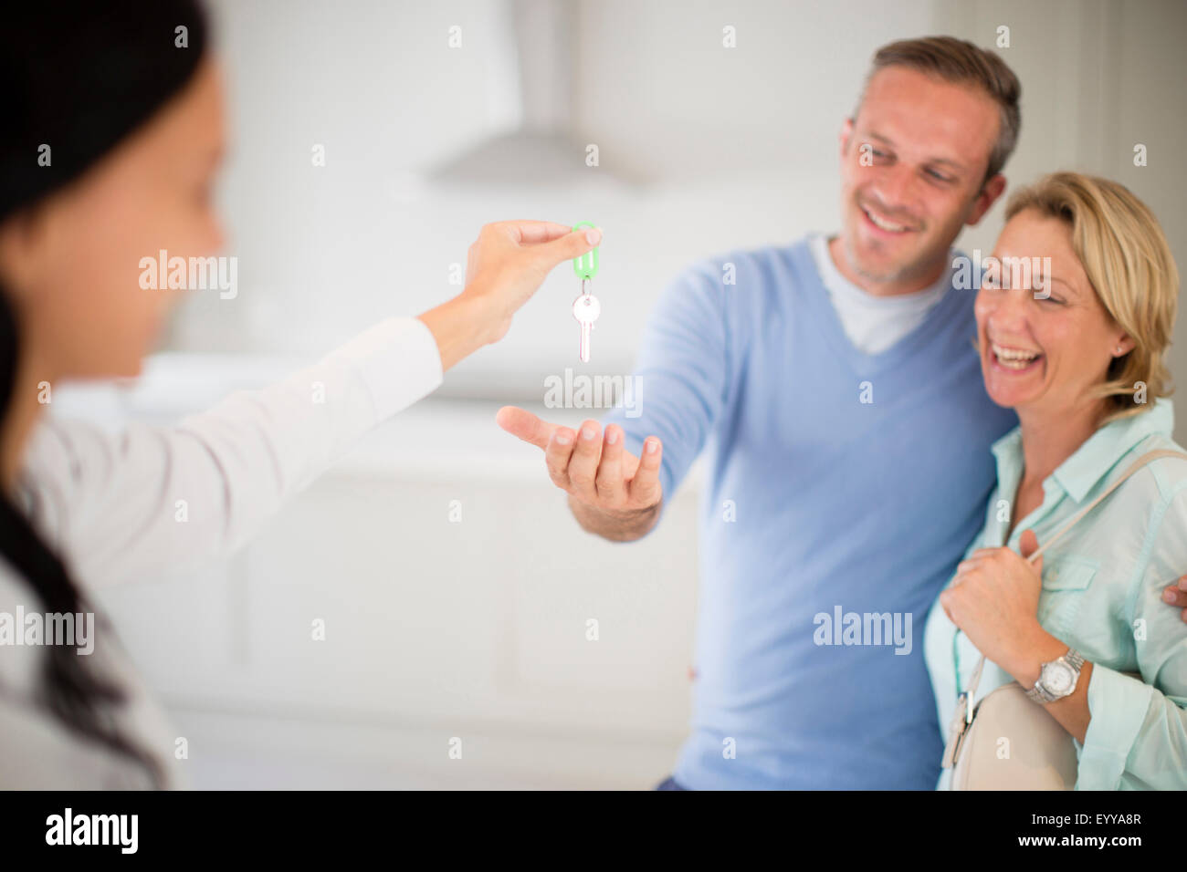 Realtor giving couple keys to new home Stock Photo