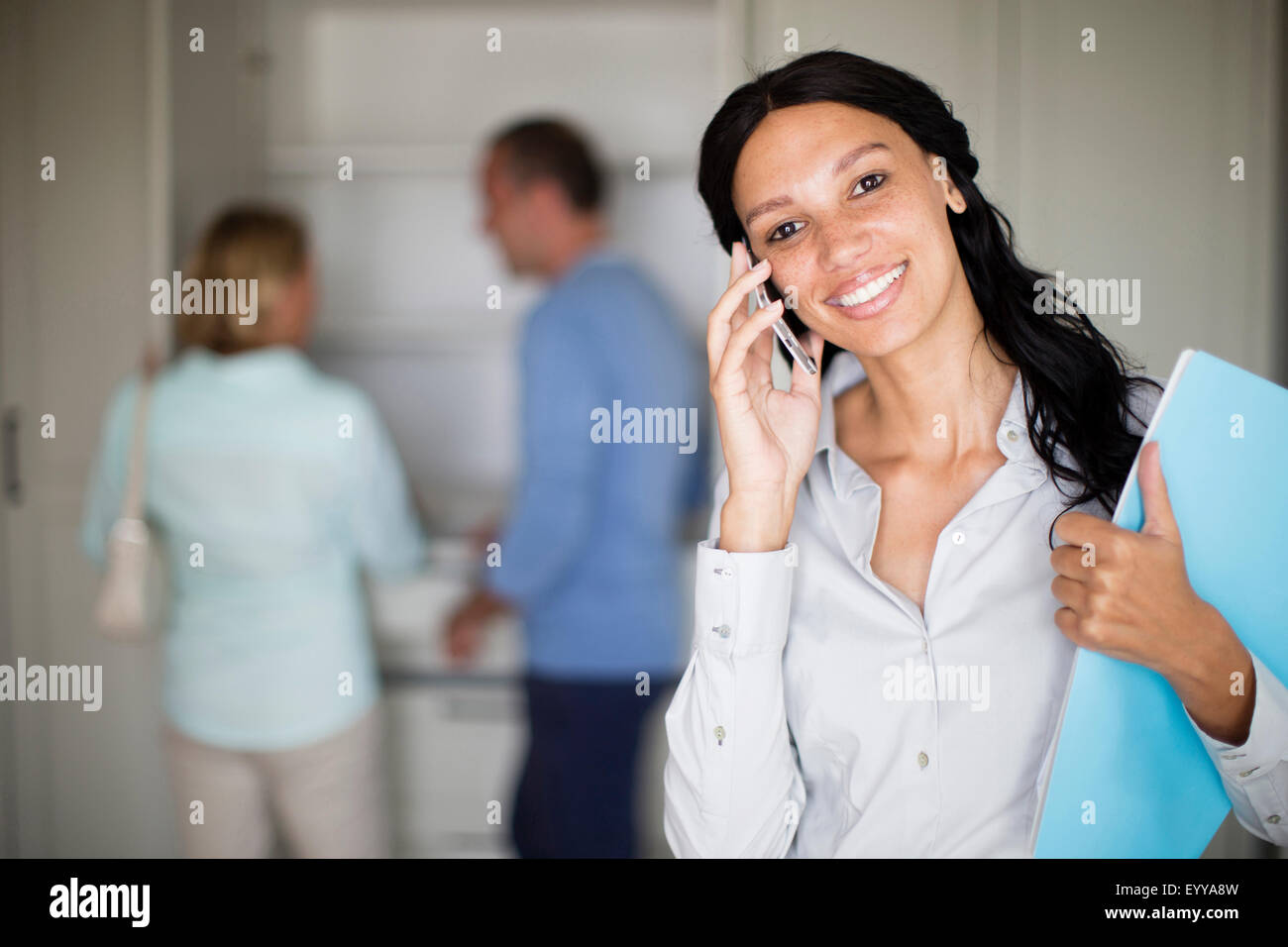 Realtor talking on cell phone with couple in new home Stock Photo