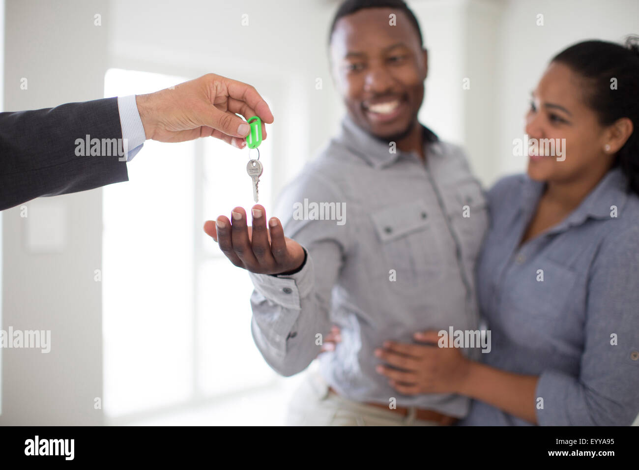 Realtor giving couple keys to new home Stock Photo