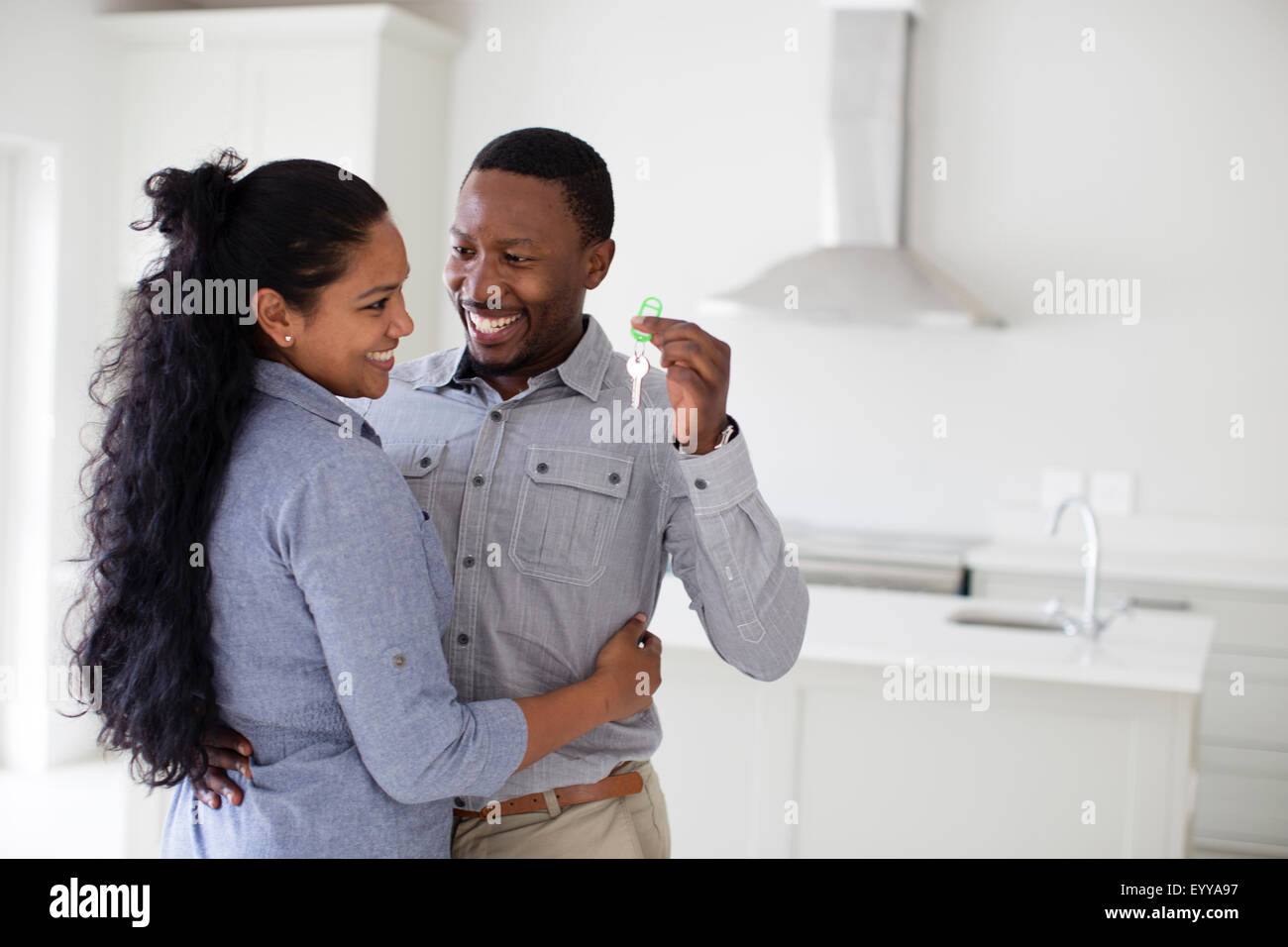 Couple hugging and holding keys in new home Stock Photo