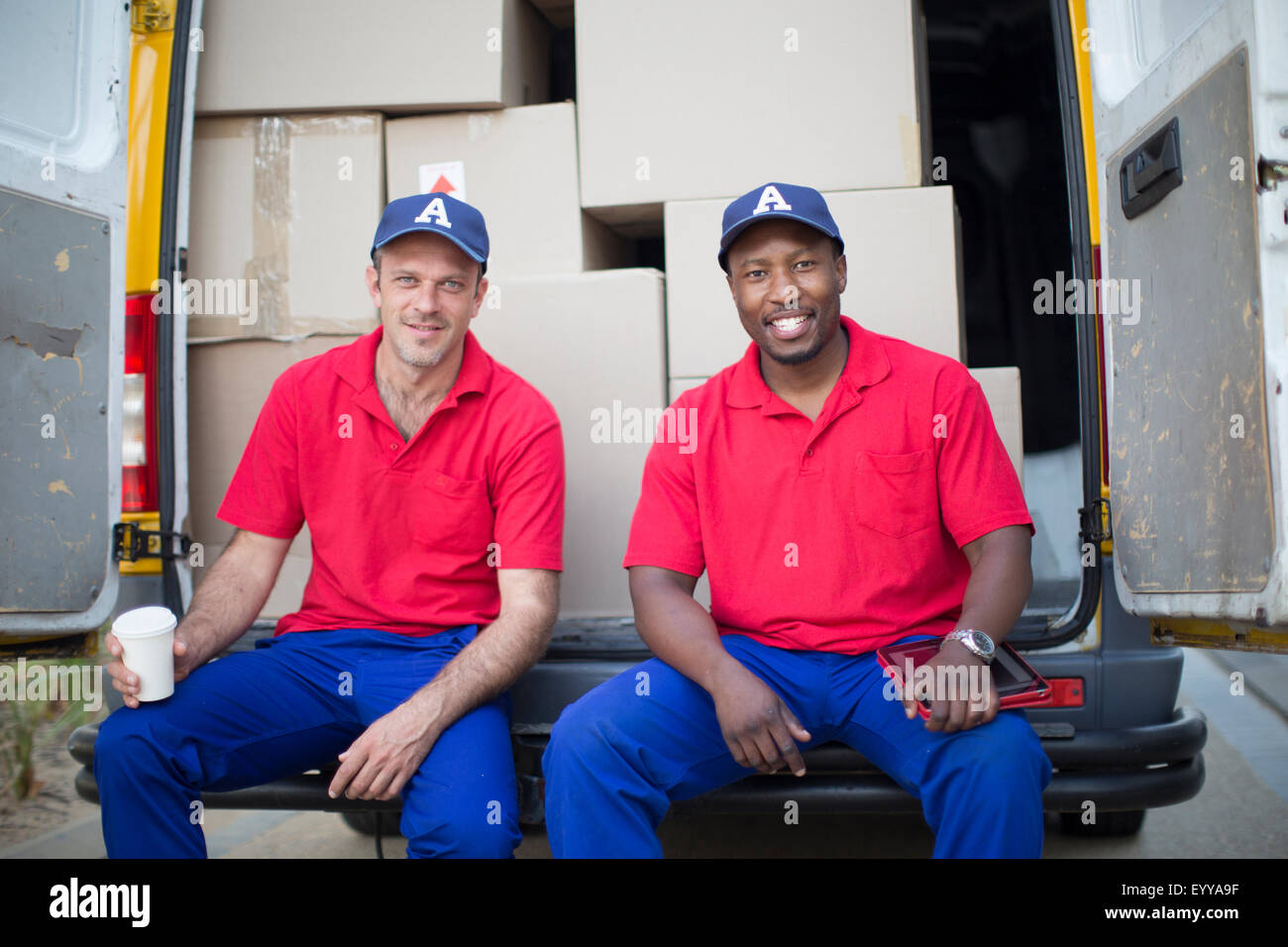 Delivery men sitting with packages in van Stock Photo