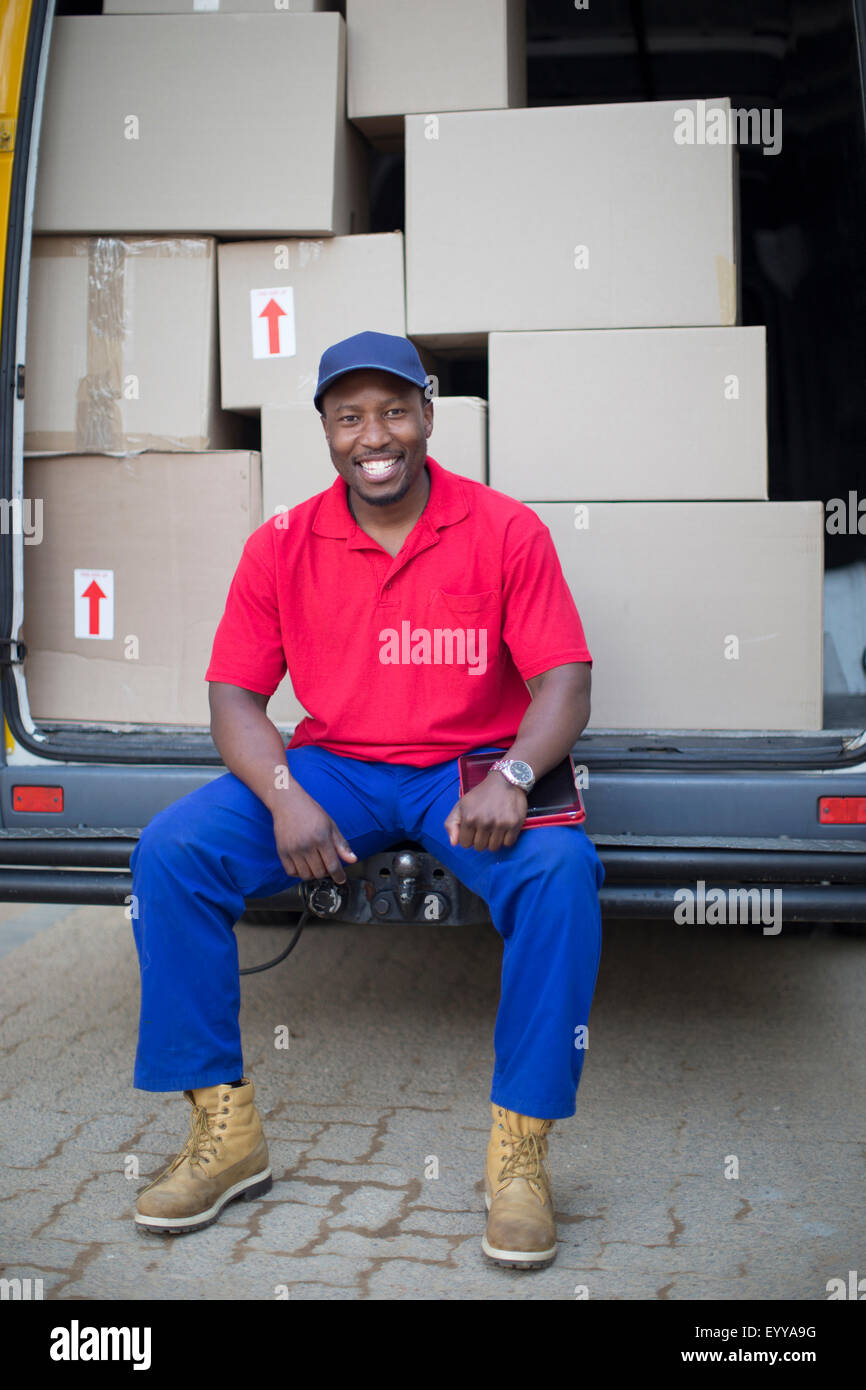 Black delivery man sitting with packages in van Stock Photo
