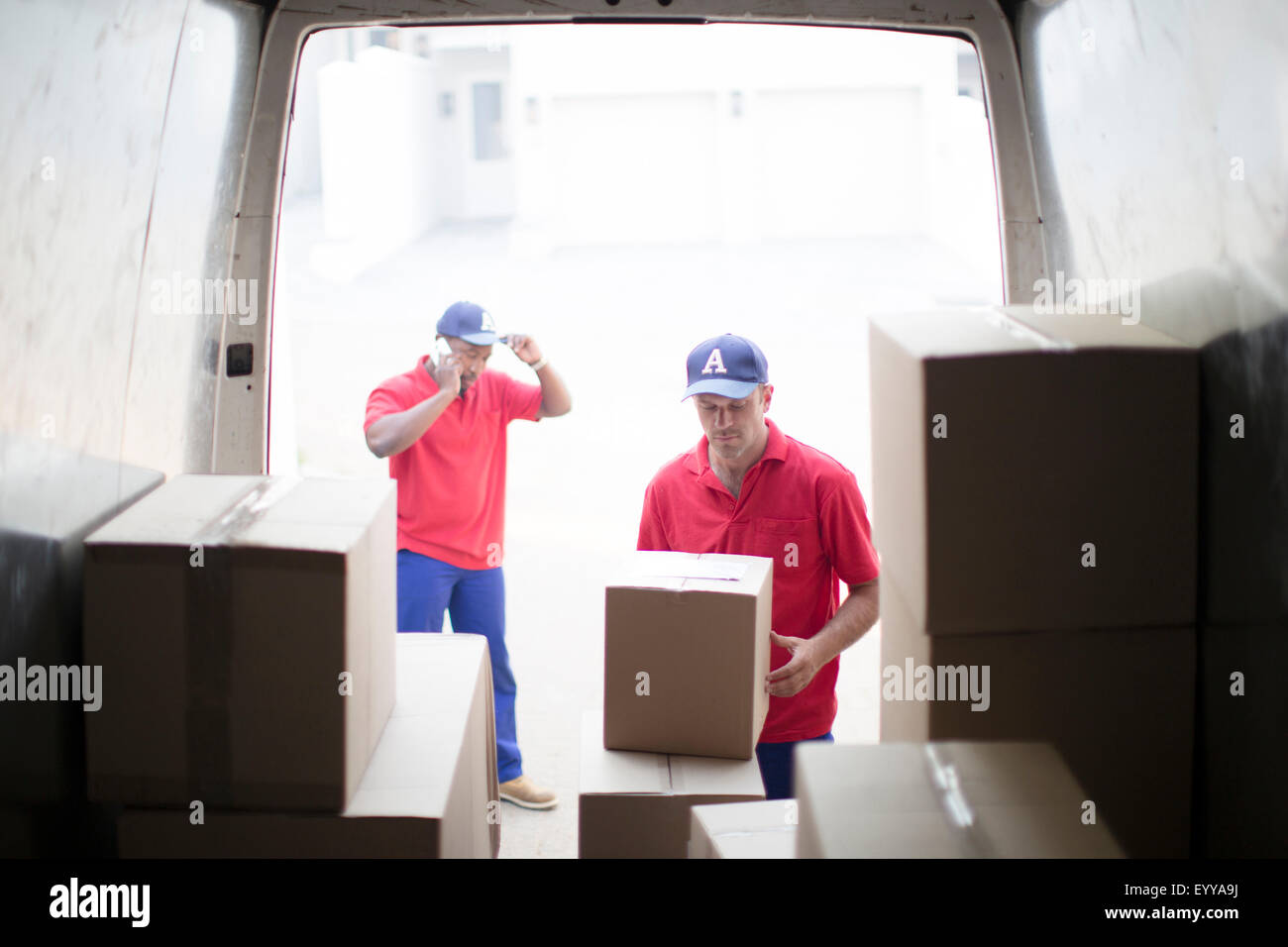 Delivery men unloading packages in van Stock Photo