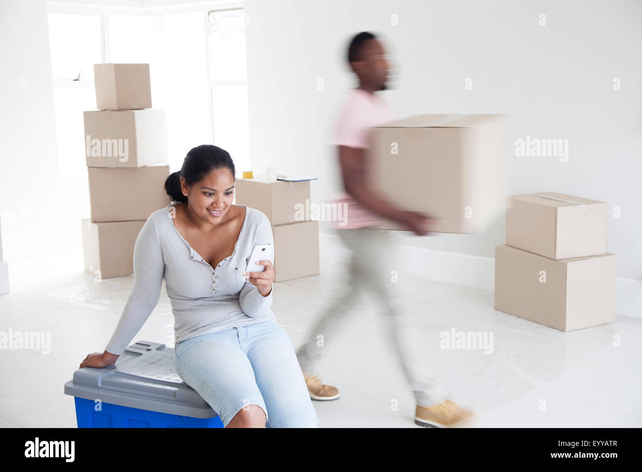 Woman relaxing with man carrying boxes in new home Stock Photo