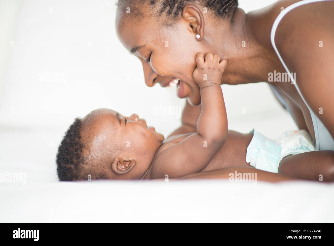Black mother and baby playing on bed Stock Photo