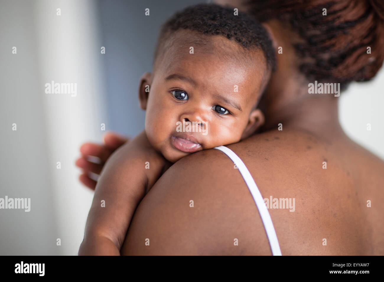 Close up of Black mother burping baby over her shoulder Stock Photo