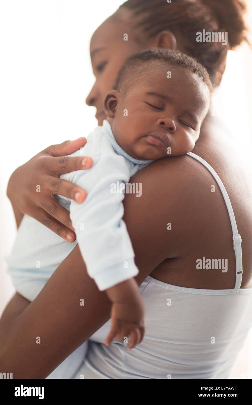 Close up of Black mother holding sleeping baby Stock Photo