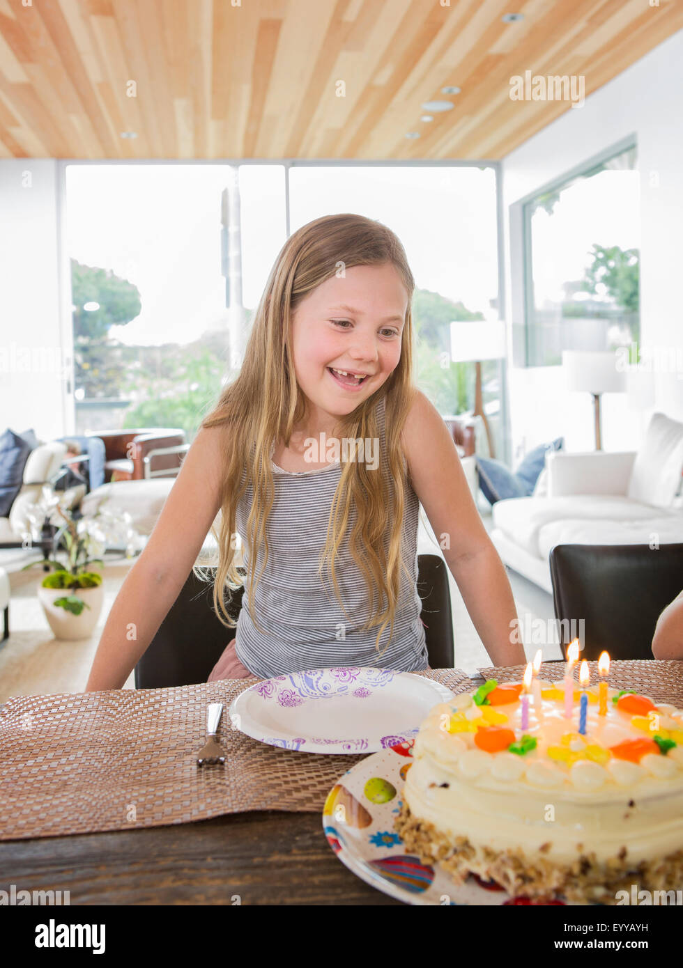 Caucasian girl admiring birthday cake at party Stock Photo