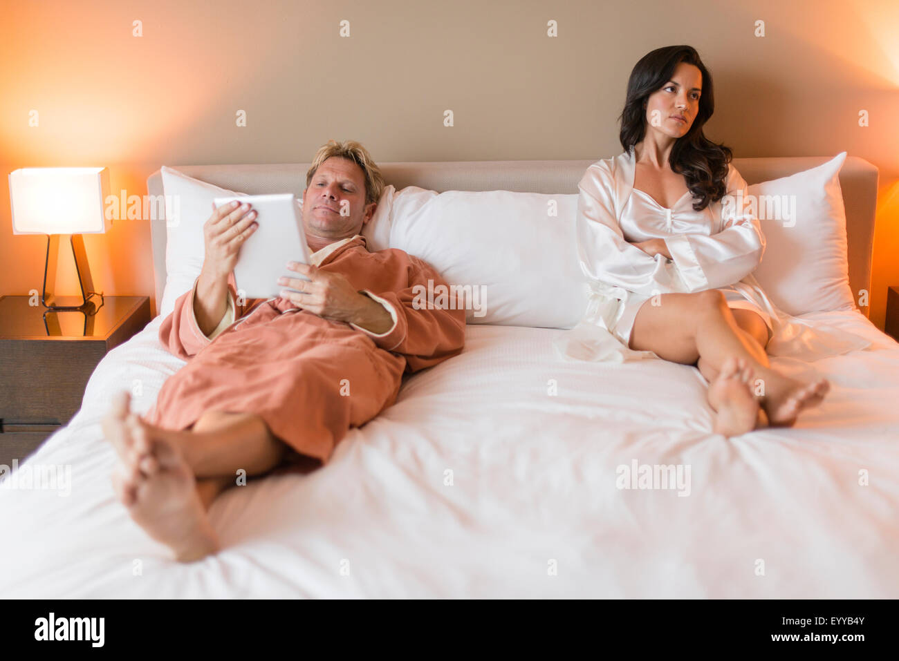 Man with digital tablet ignoring girlfriend in bed Stock Photo