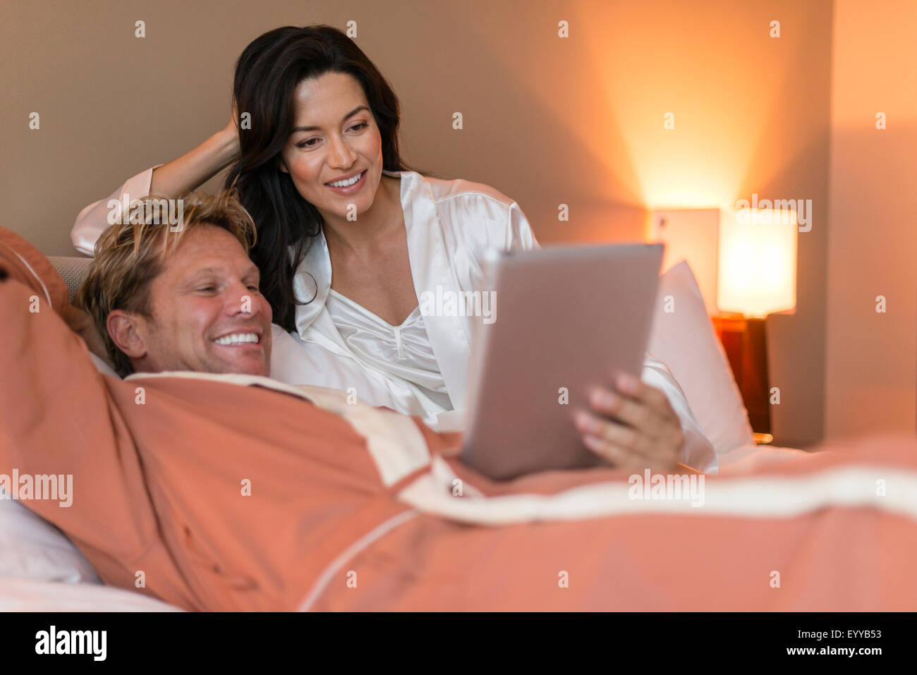Couple using digital tablet on bed Stock Photo