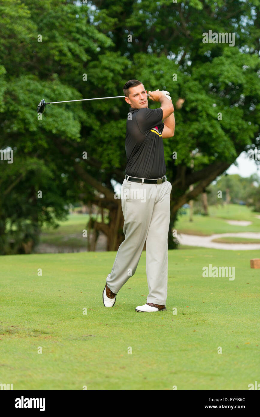 Caucasian man swinging club on golf course Stock Photo