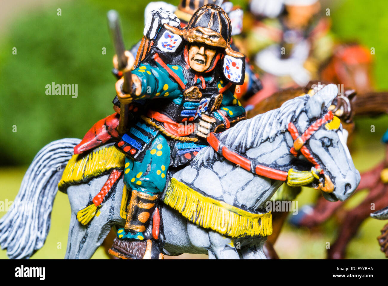 Close-up of metal painted scale model figures. Mounted Japanese samurai warrior holding sword, charging into battle. Table top war gaming. Stock Photo