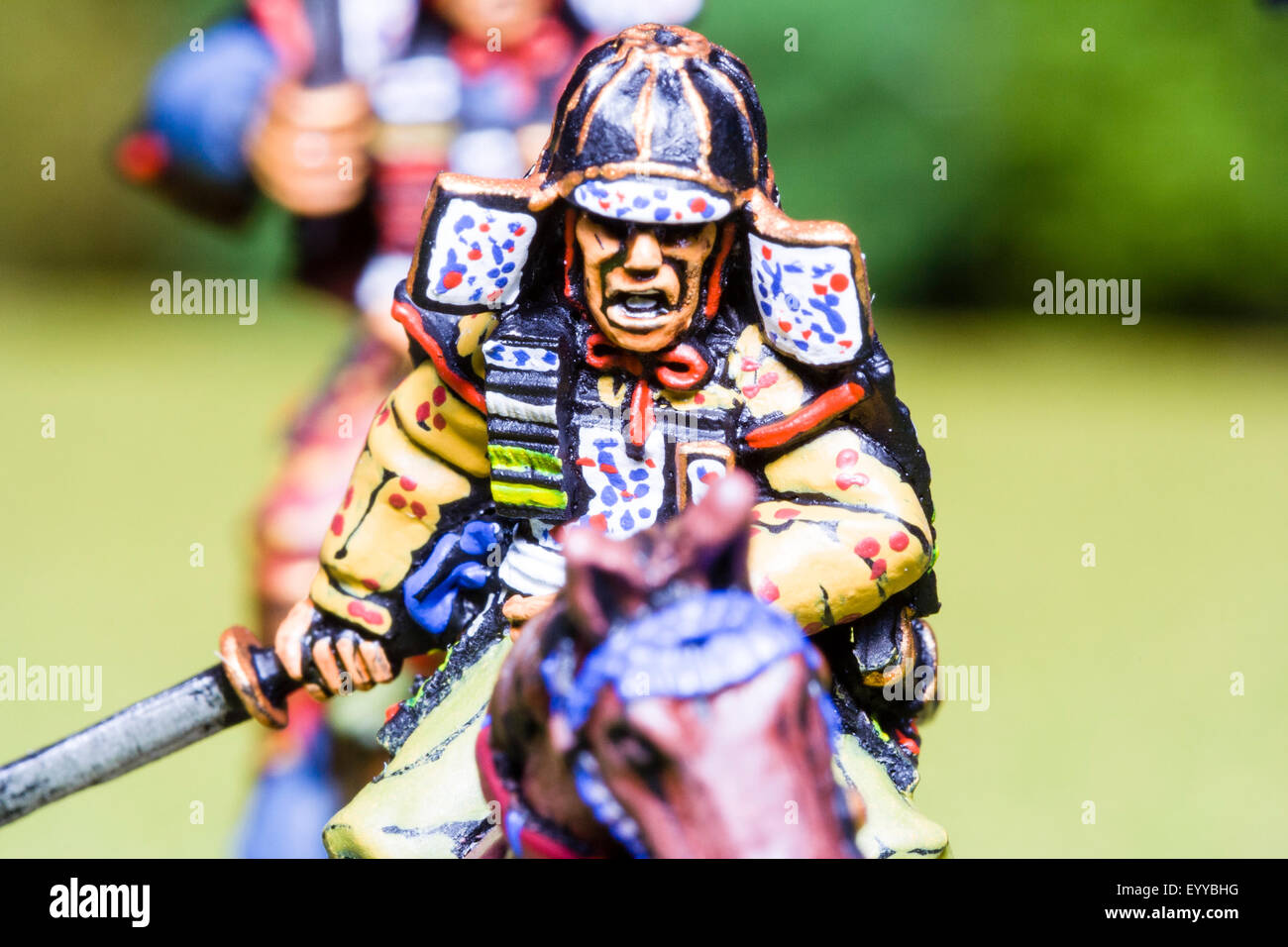 Close-up of metal painted scale model figures. Mounted Japanese samurai warrior holding sword, charging into battle. Table top war gaming. Stock Photo