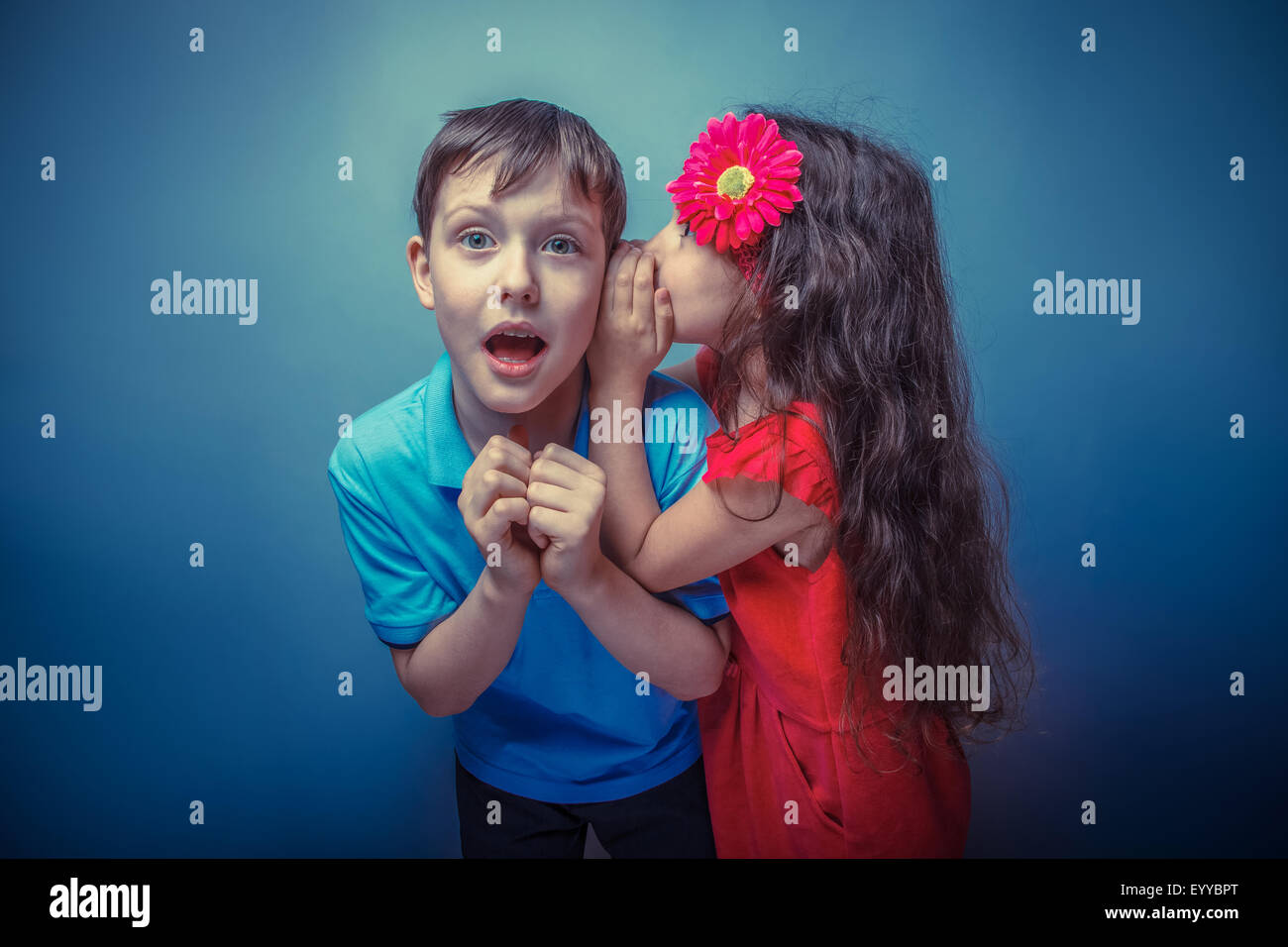 Teenage girl whispering in the ear of a secret teen boys on a  g Stock Photo