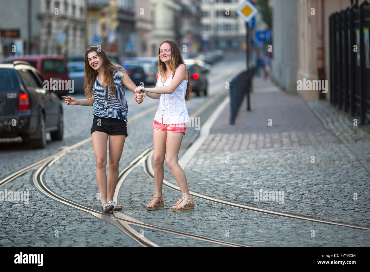 Funny teenage girls together walking on the pavement on the street. Stock Photo