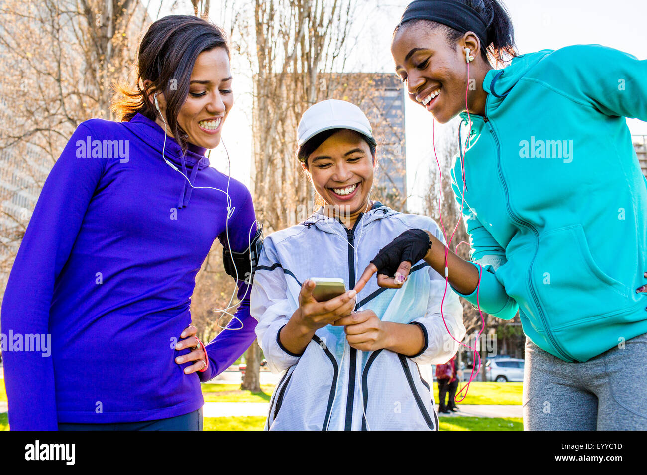 Runners using cell phone in urban park Stock Photo