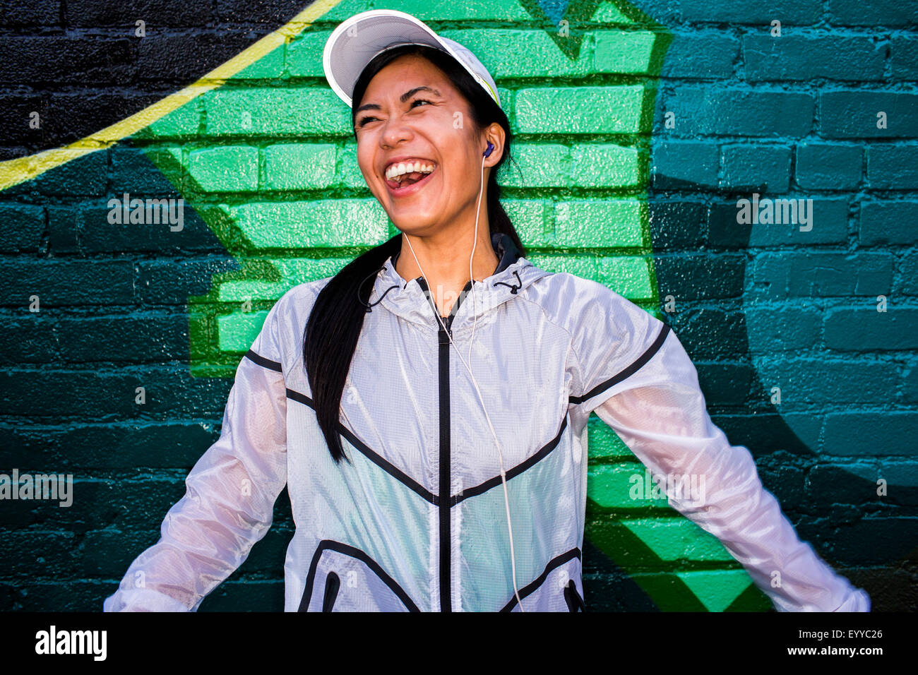 Asian runner standing near graffiti wall Stock Photo