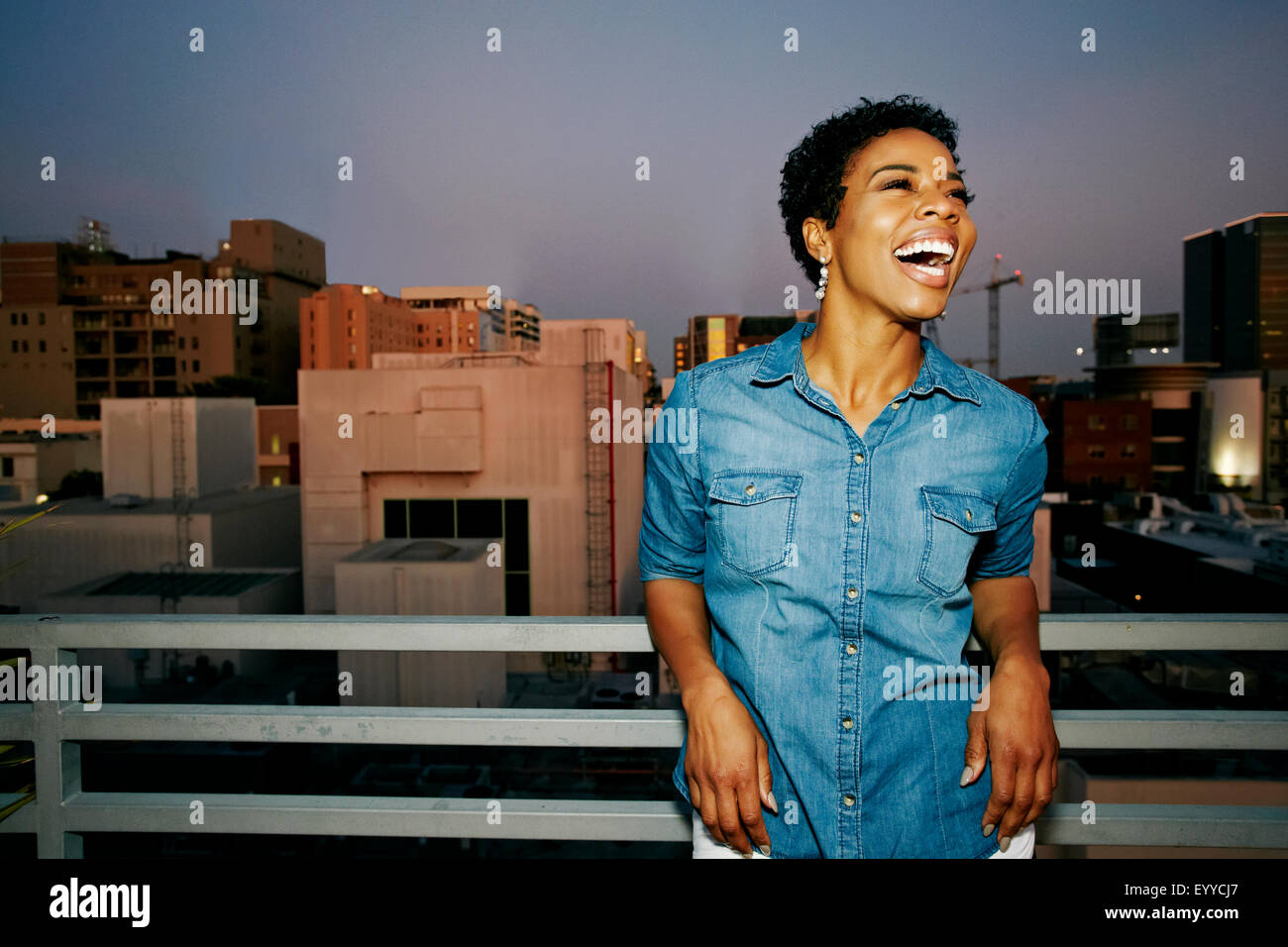 Woman laughing on urban rooftop Stock Photo