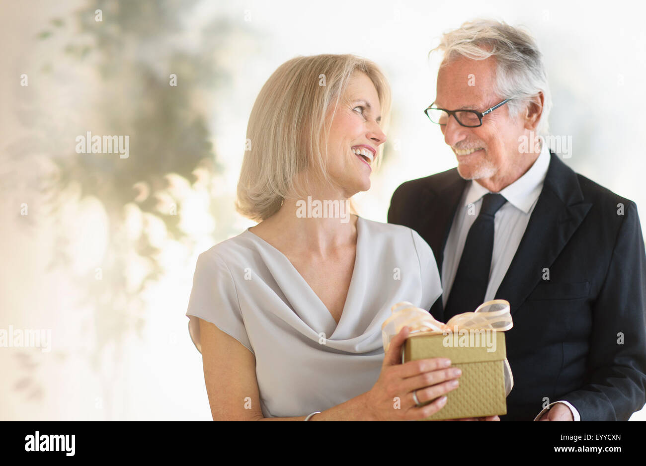 Smiling older Caucasian man giving wife a gift Stock Photo