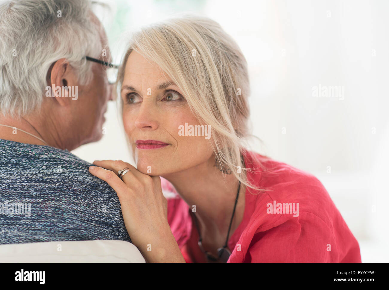 Close up of older Caucasian couple whispering Stock Photo