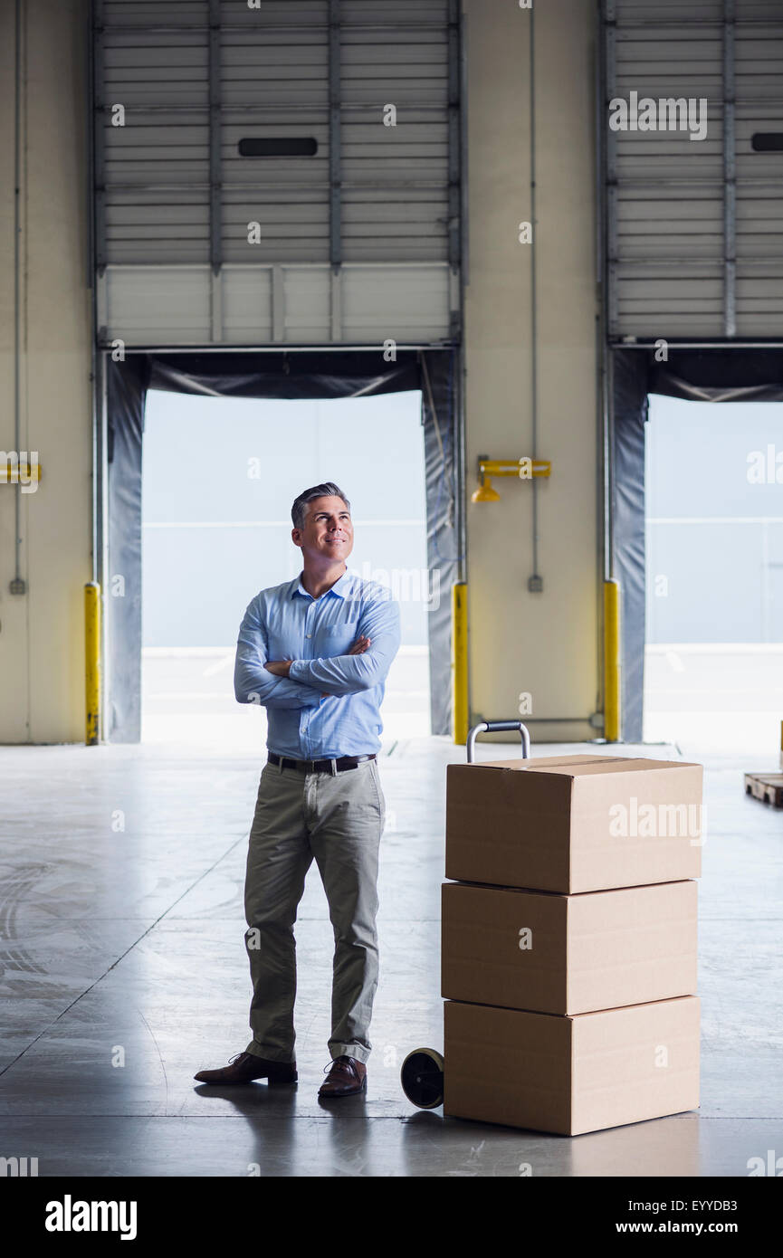 Caucasian businessman standing near cardboard boxes in warehouse Stock Photo