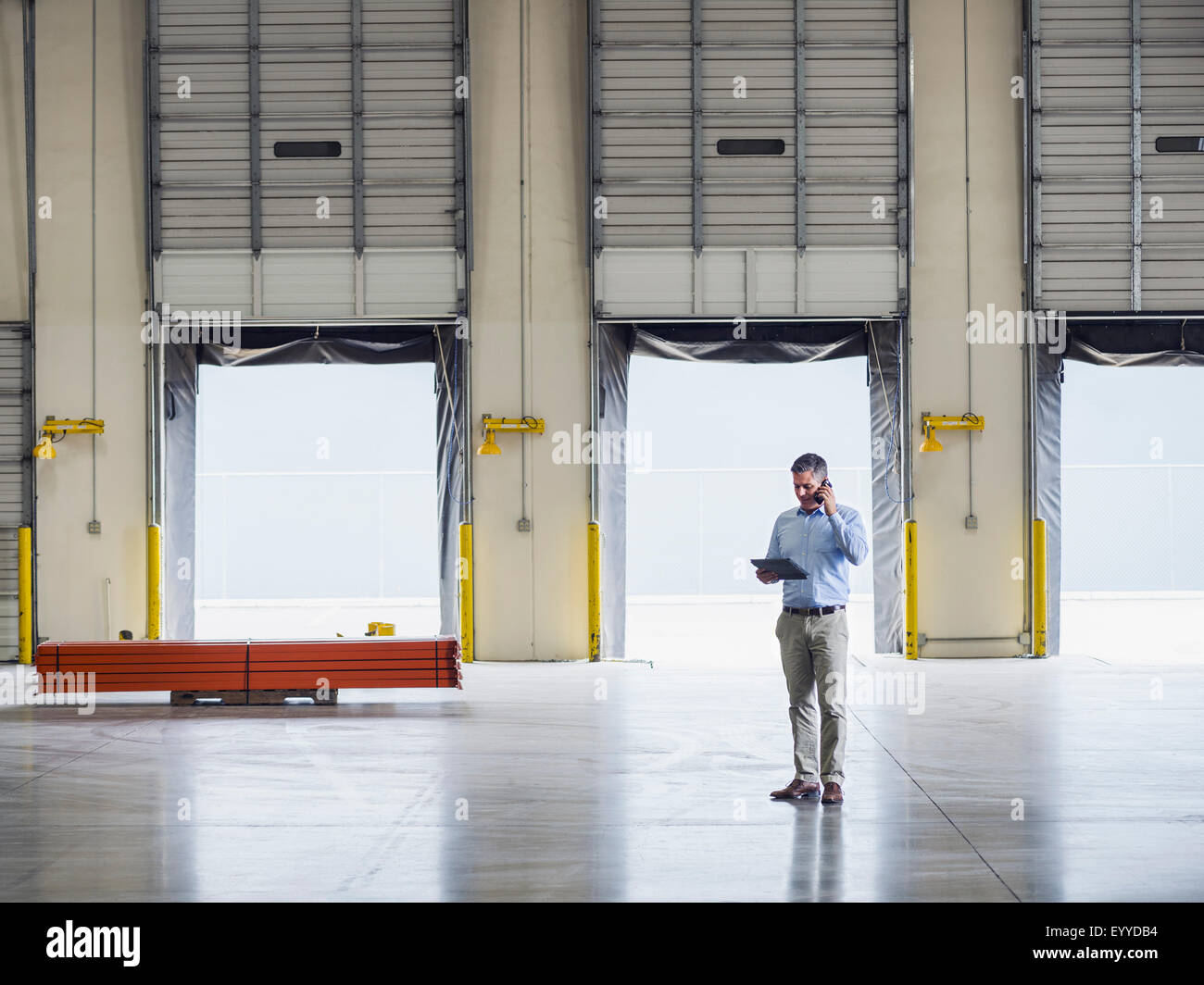 Caucasian businessman talking on cell phone in warehouse Stock Photo