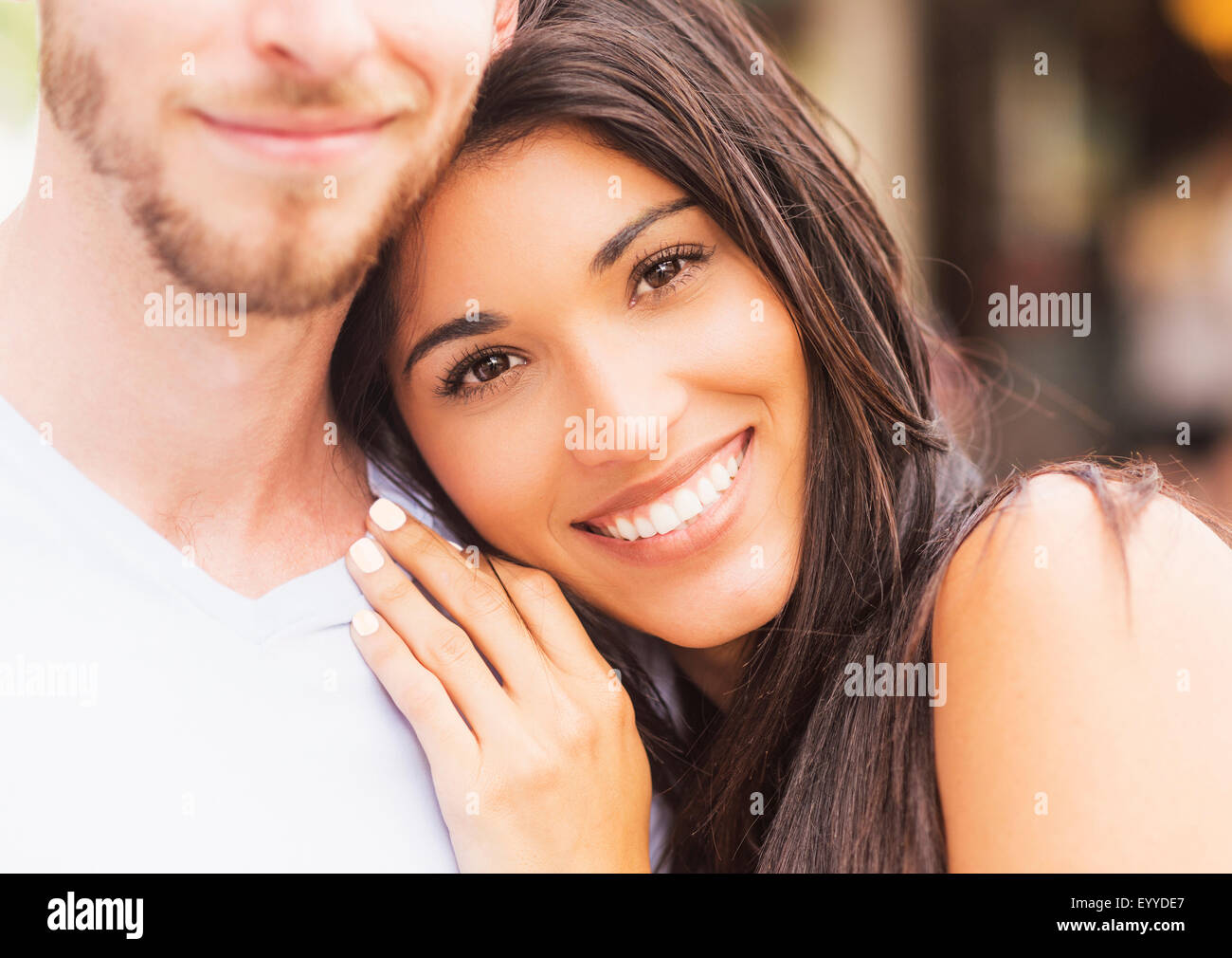 Hispanic woman hugging boyfriend on sidewalk Stock Photo
