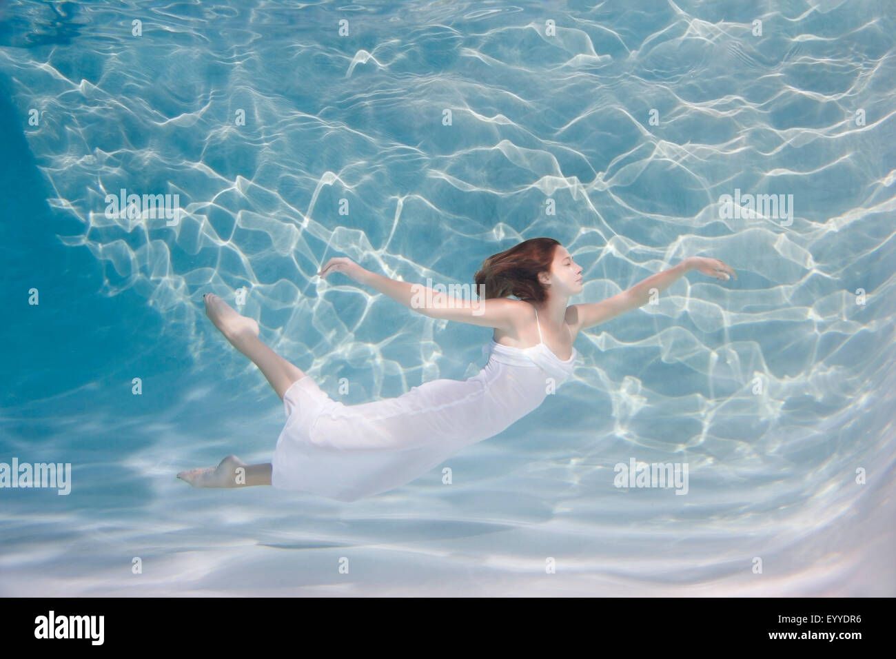 Underwater view of Caucasian woman in dress swimming in pool Stock Photo