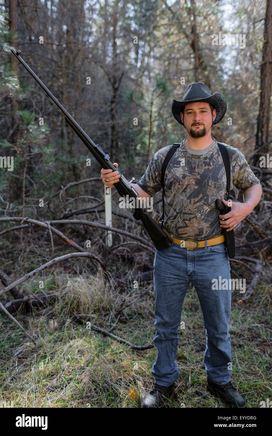 Caucasian hunter holding gun in forest Stock Photo
