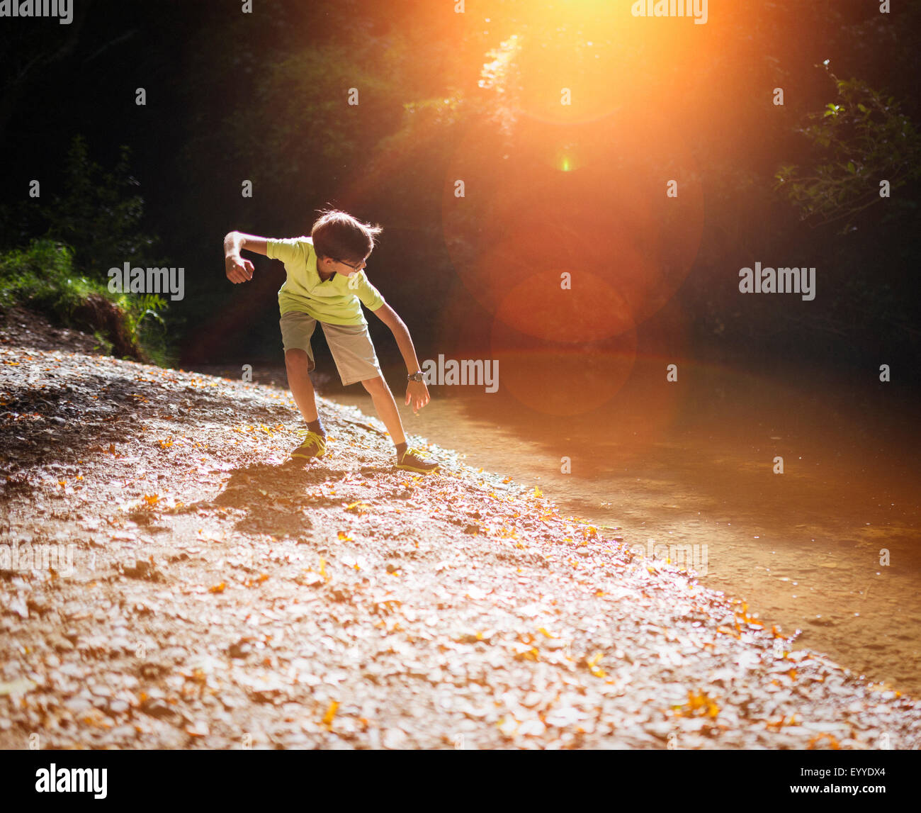 Mixed race boy skipping stones in stream Stock Photo