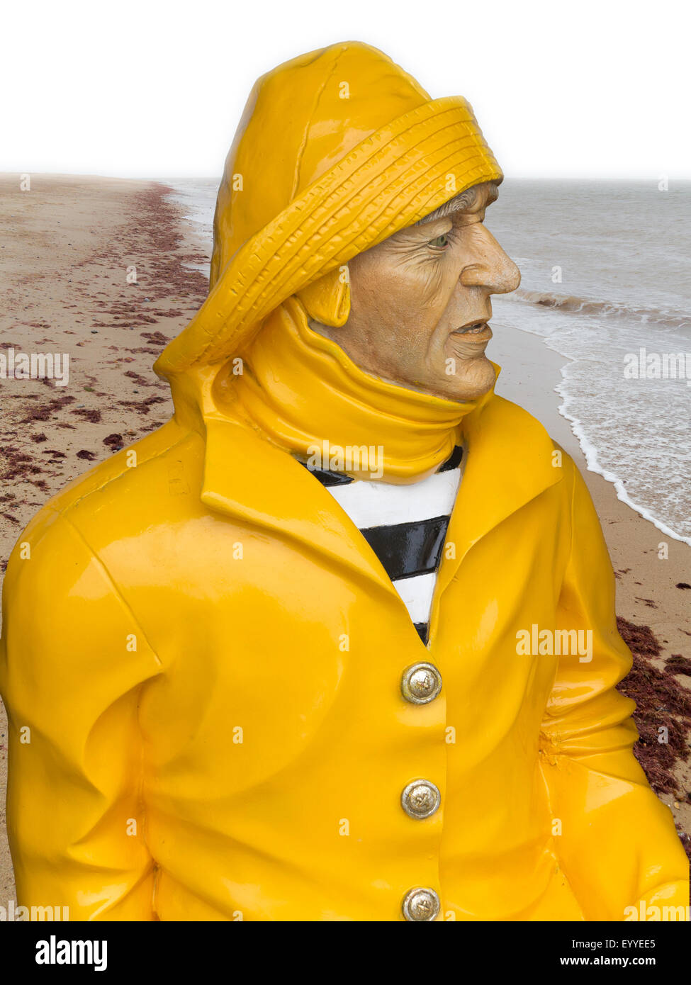 A painted sculpture of a fisherman wearing bright yellow waterproofs and sou'wester Norfolk manipulated onto beach location Stock Photo