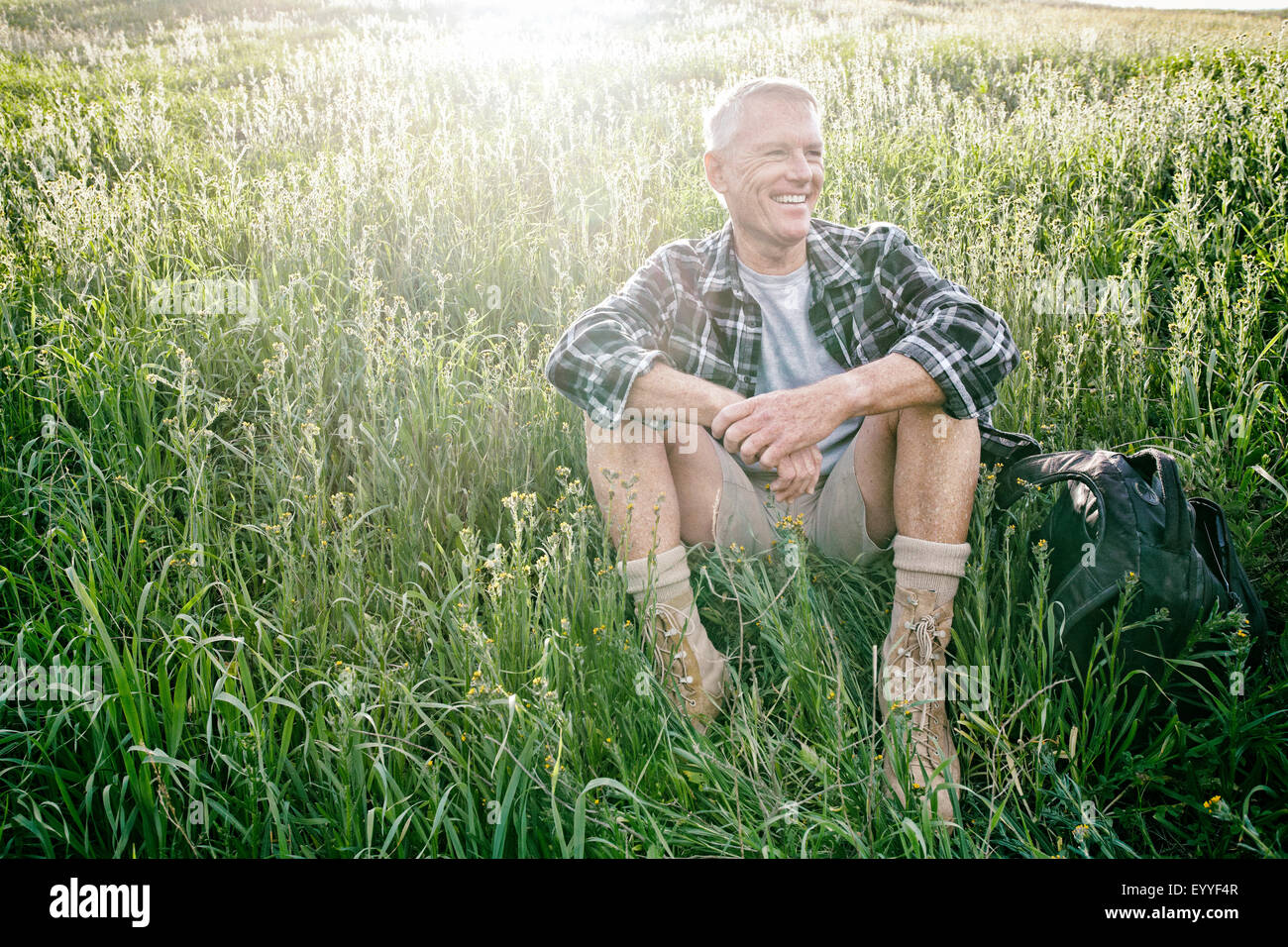 Older Caucasian man sitting on grassy hillside Stock Photo