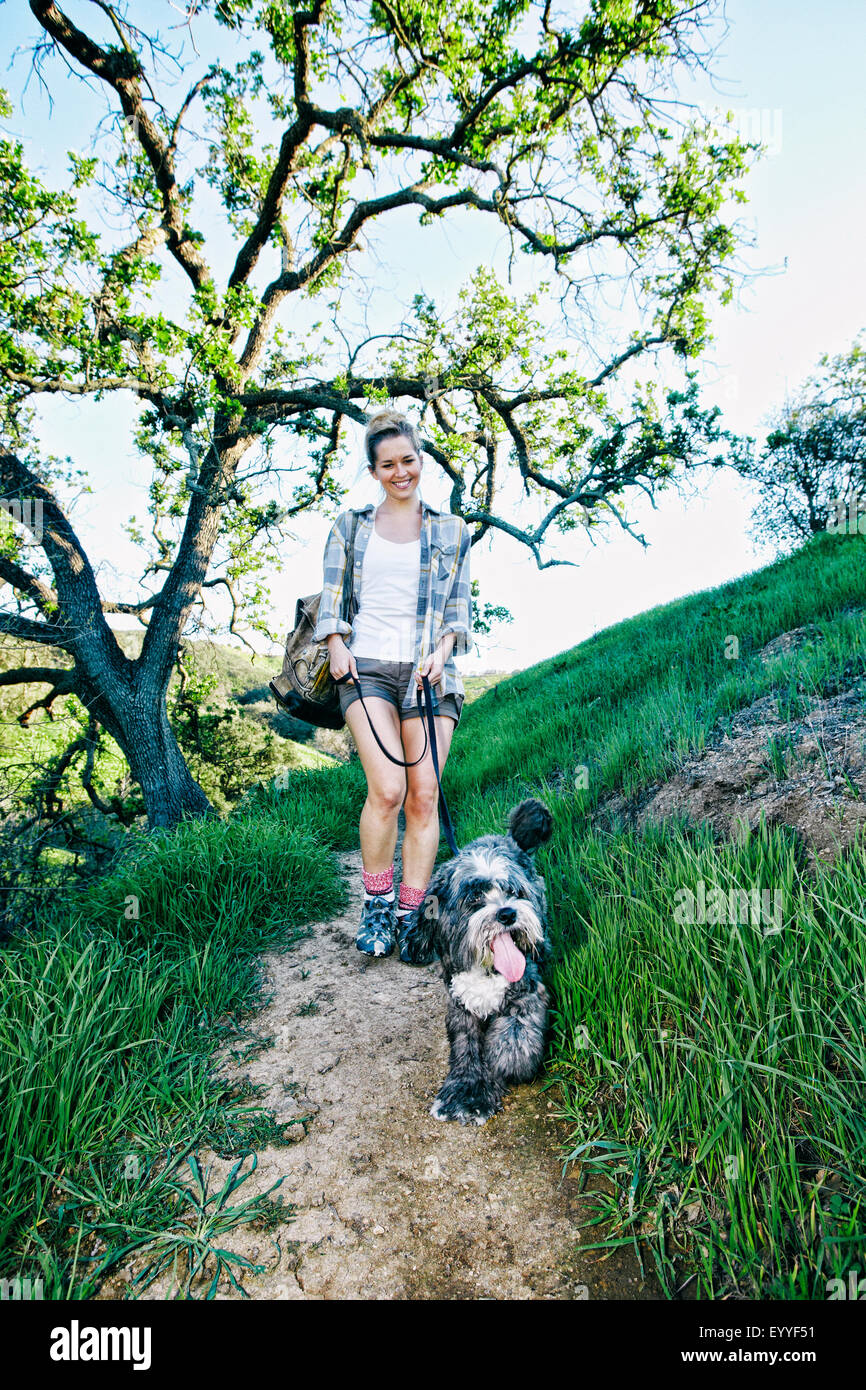 Caucasian woman walking dog on grassy hillside Stock Photo