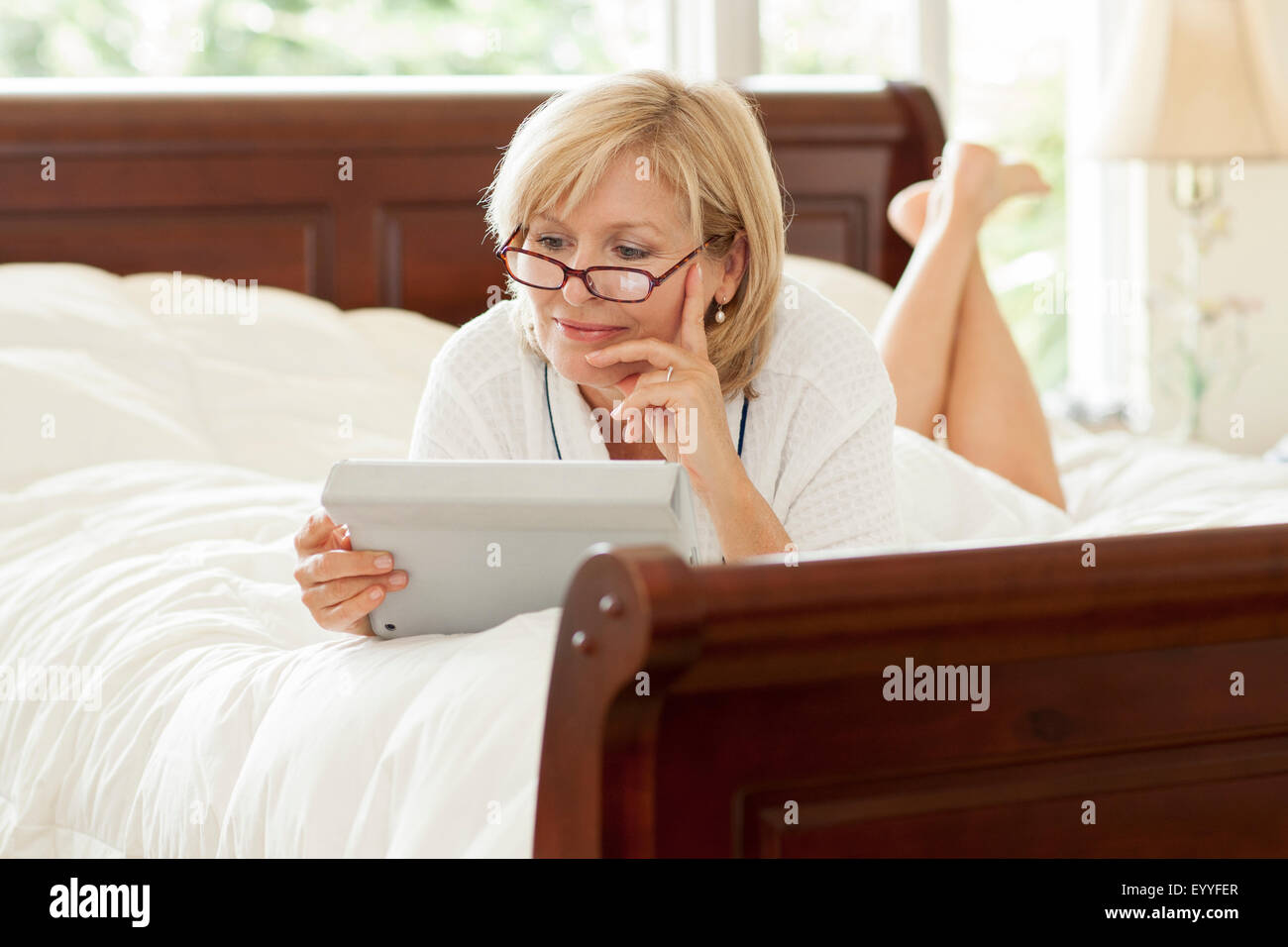 Caucasian woman using digital tablet on bed Stock Photo