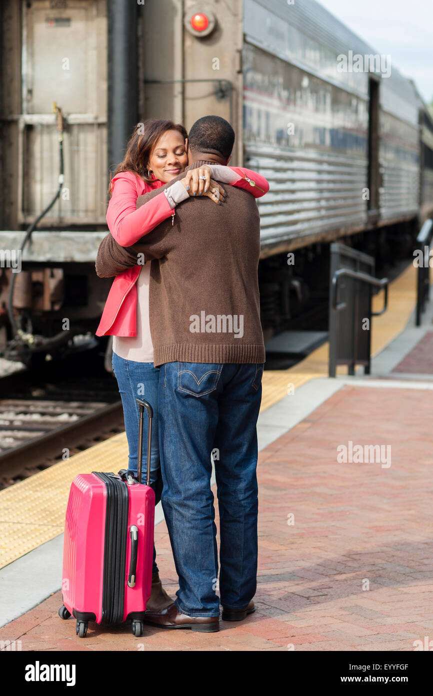 Couple hugging at train station Stock Photo