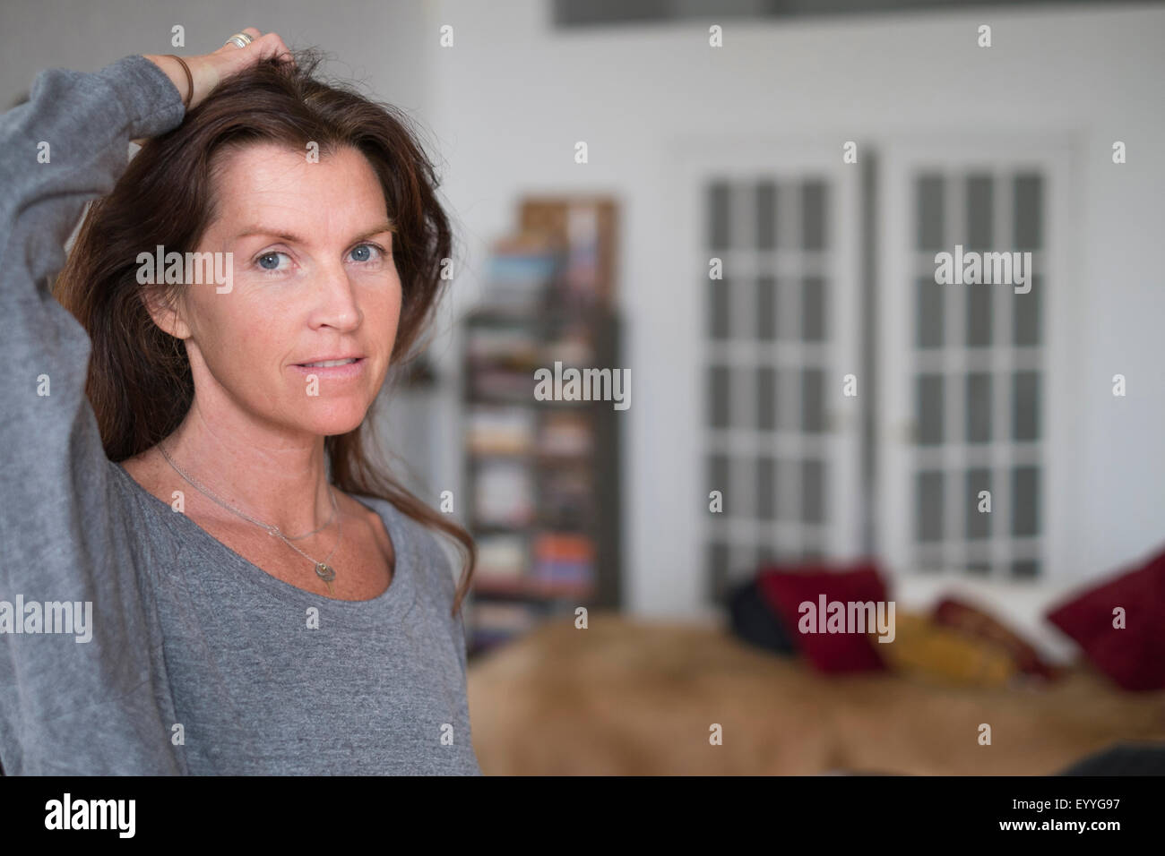 Caucasian woman in living room with hand in hair Stock Photo