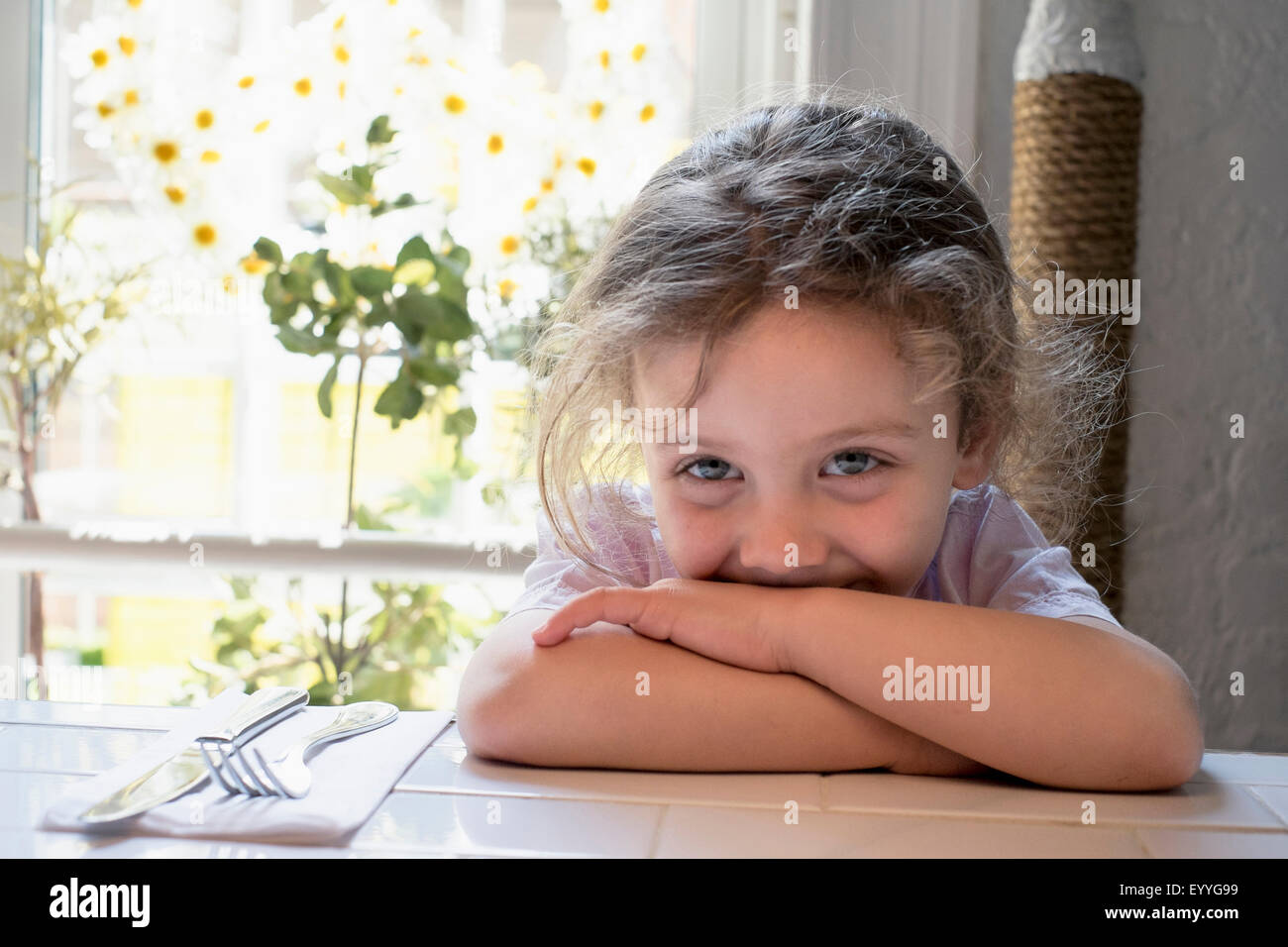 Caucasian girl leaning on kitchen table Stock Photo