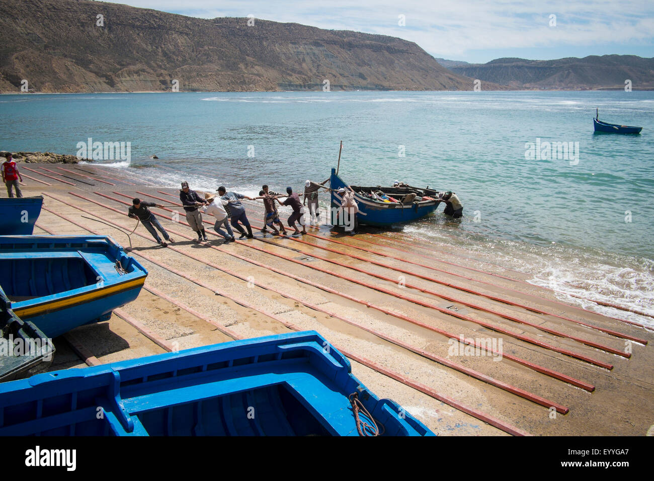 People pulling boat onto boat ramp Stock Photo