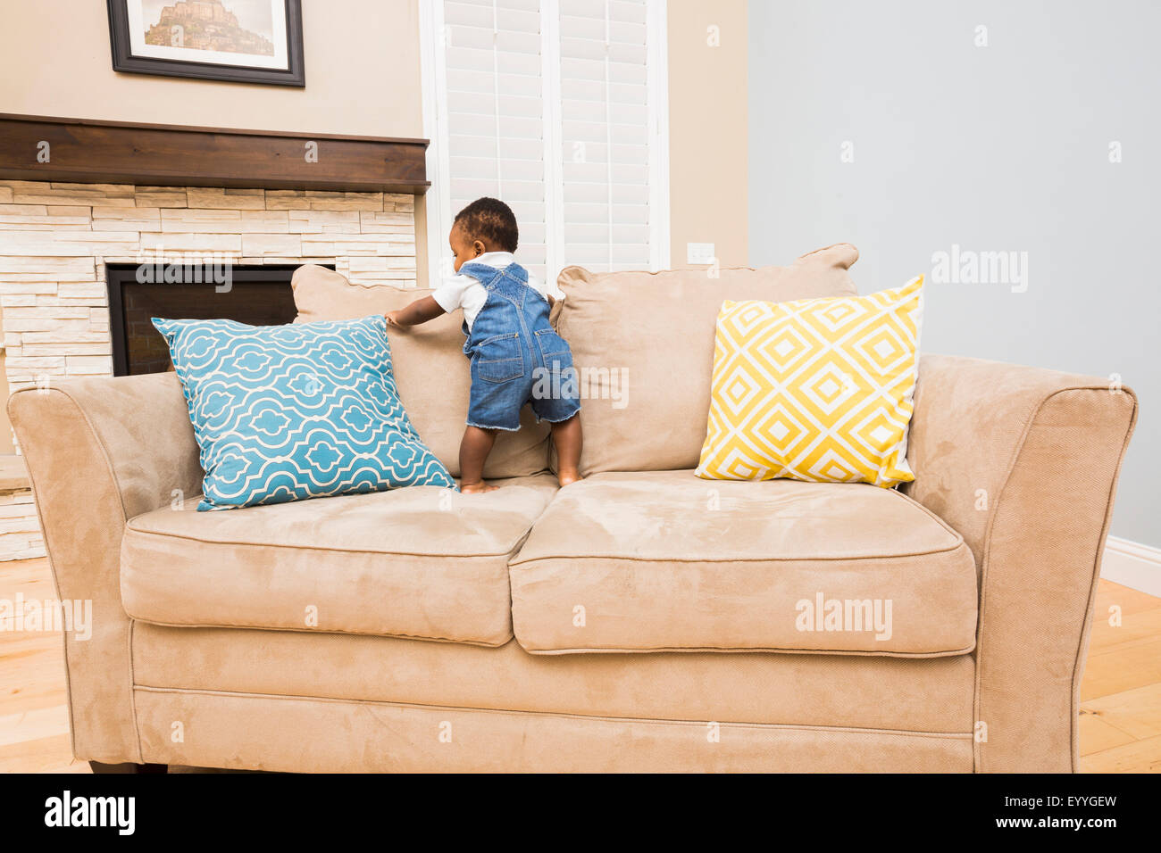 Black baby climbing on sofa in living room Stock Photo Alamy