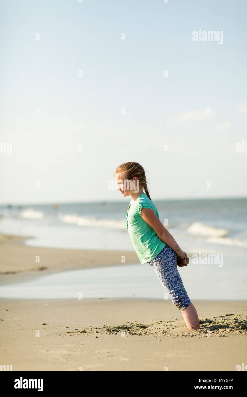 Caucasian girl leaning in sand on beach Stock Photo