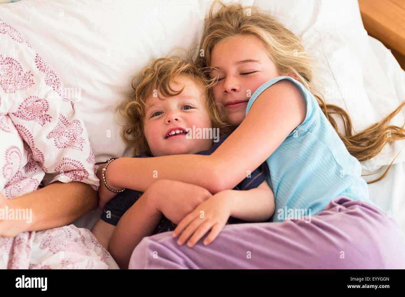 Caucasian brother and sister cuddling on bed Stock Photo