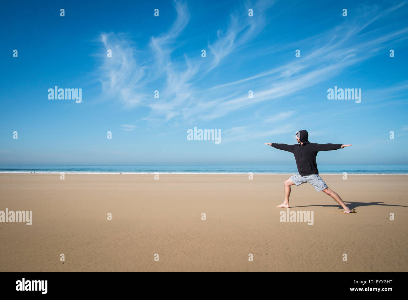 Caucasian man practicing yoga on beach Stock Photo