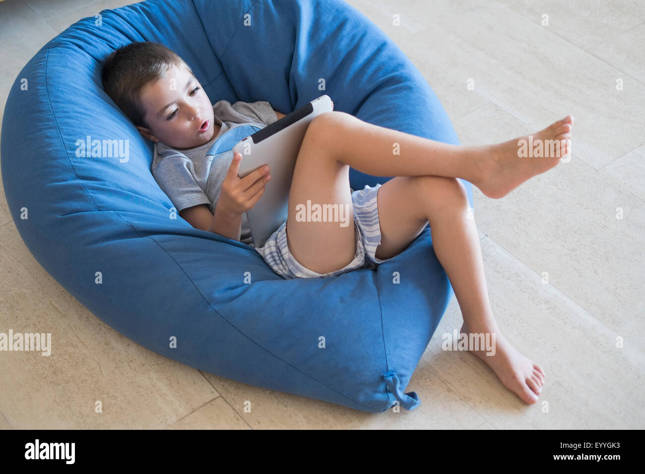 Caucasian boy using digital tablet in beanbag chair Stock Photo