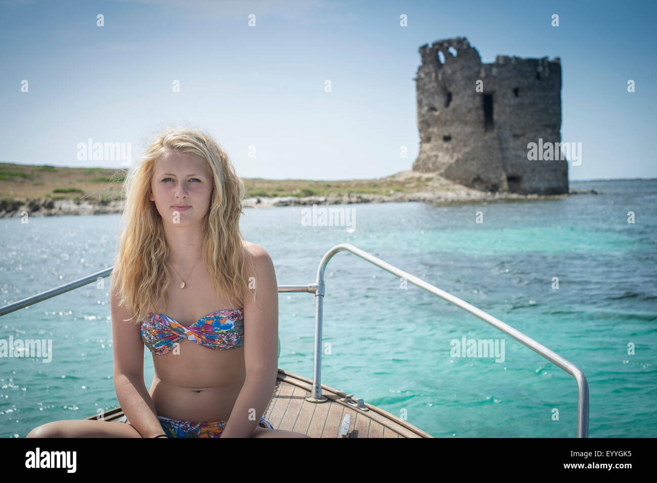 Smiling girl sunbathing on sailboat near ancient ruins Stock Photo