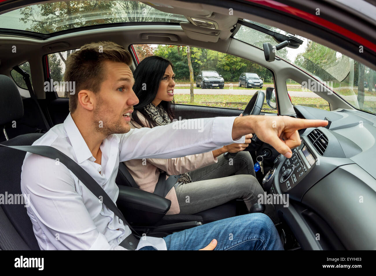 young woman driving car with gesticulating man as co-driver, Austria Stock Photo